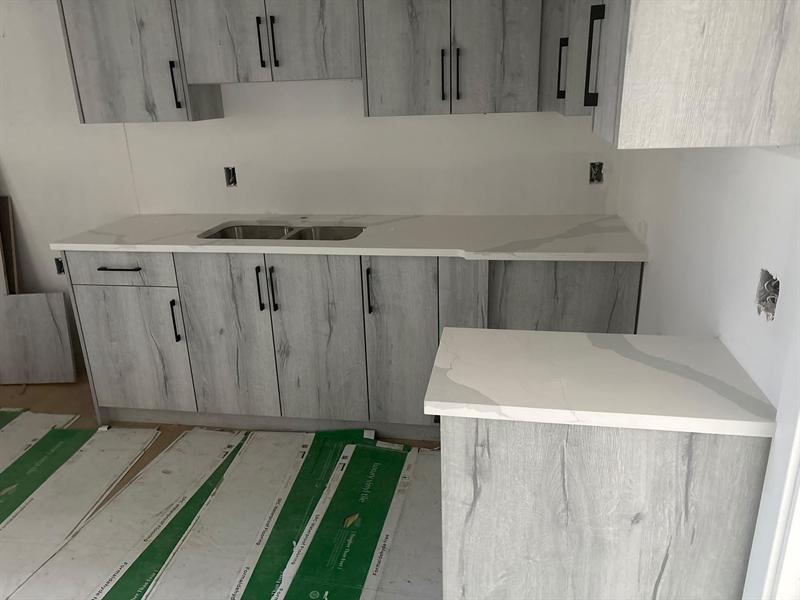 Driftwood grey wood-grain flat-panel cabinets with long black handles