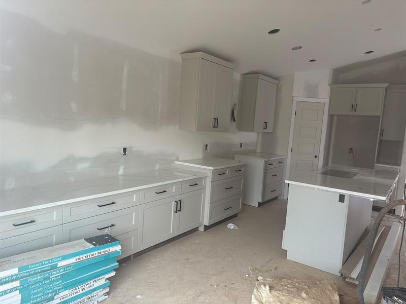 Greige shaker cabinets with black bar pulls and a white quartz countertop