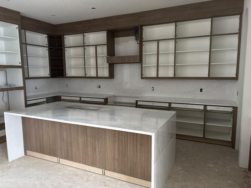 Walnut-finish island with a white quartz waterfall top and matching walnut-framed upper cabinets