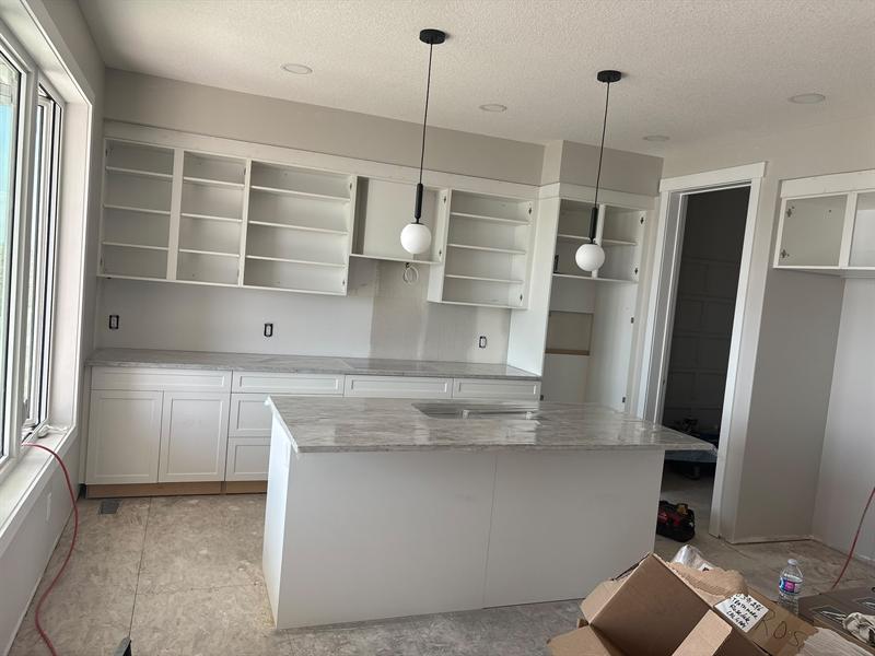 Grey and white veined stone countertops on a white island and perimeter cabinets